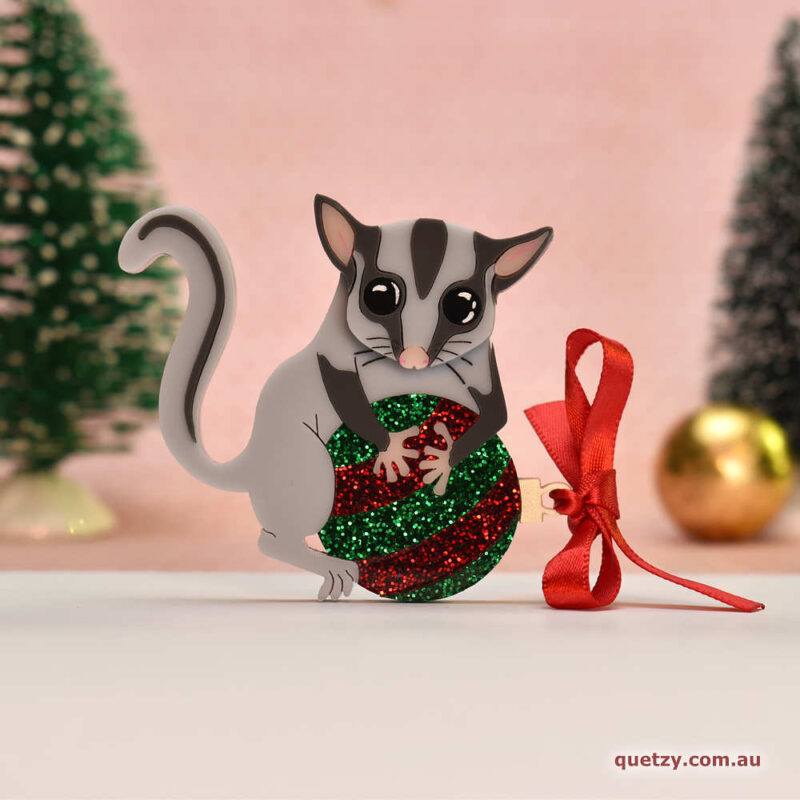 Lottie the Leadbeater's Possum with glitter red and green bauble. A Christmas themed acrylic brooch, designed and handmade by Quetzy.