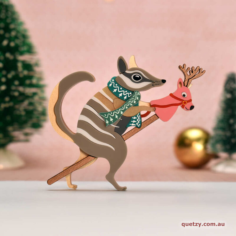 Nimble Numbat riding a toy stick reindeer. A Christmas themed acrylic brooch, designed and handmade by Quetzy.