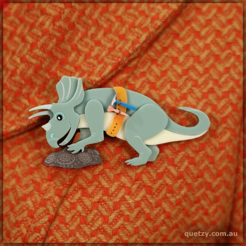 A unique Palaentolgy brooch depicting a Triceratops excavating Ammonites at a fossil dig. Acrylic brooch designed and handmade by Quetzy